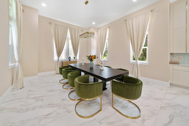 dining space with a wealth of natural light, marble finish floor, a notable chandelier, and baseboards