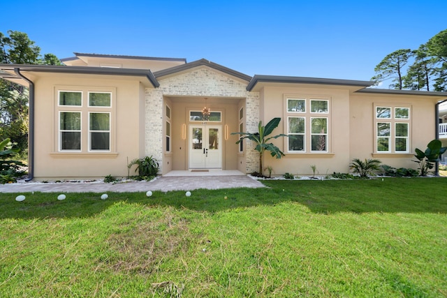 prairie-style house featuring french doors, stucco siding, and a front lawn