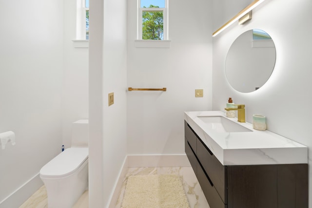 half bathroom featuring toilet, baseboards, and vanity