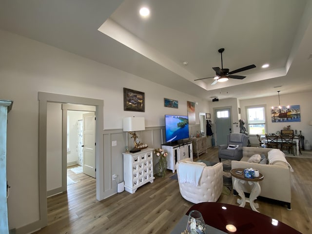 3784 Redbud Way, Panama City, FL 32404 - living room with a wainscoted wall, a decorative wall, wood finished floors, ceiling fan with notable chandelier, and a tray ceiling