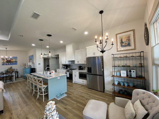 3784 Redbud Way, Panama City, FL 32404 - kitchen featuring a chandelier, wood finished floors, a kitchen bar, appliances with stainless steel finishes, and visible vents