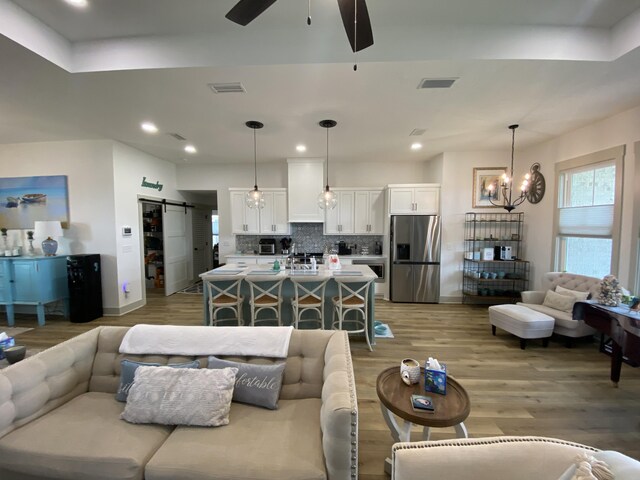 3784 Redbud Way, Panama City, FL 32404 - living area with ceiling fan with notable chandelier, visible vents, a barn door, and light wood-style flooring