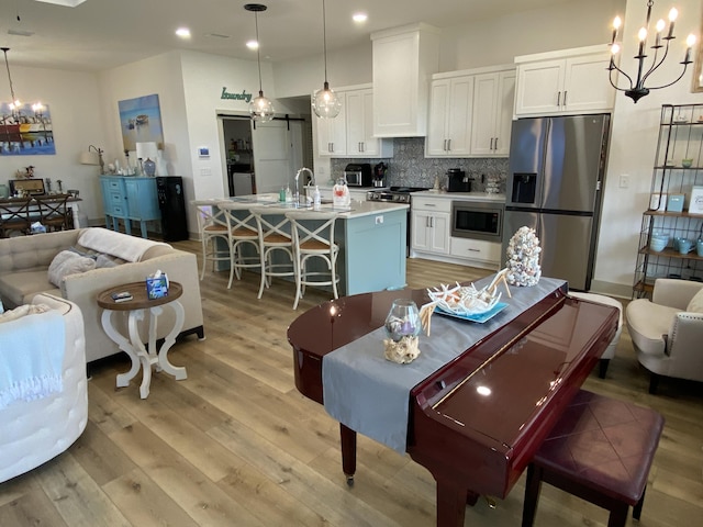 3784 Redbud Way, Panama City, FL 32404 - interior space featuring white cabinetry, an inviting chandelier, decorative backsplash, light wood-style floors, and appliances with stainless steel finishes