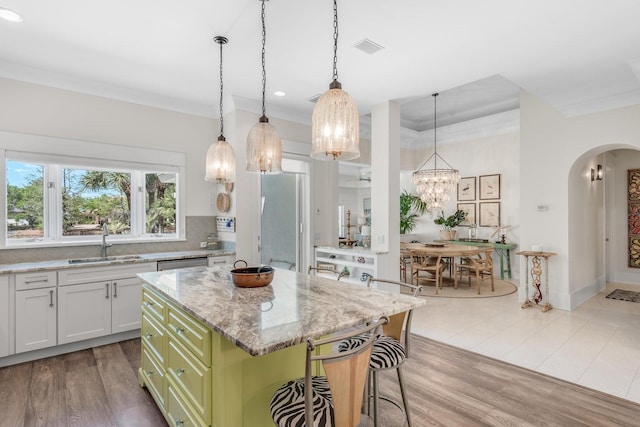 kitchen featuring a sink, a chandelier, arched walkways, decorative backsplash, and ornamental molding