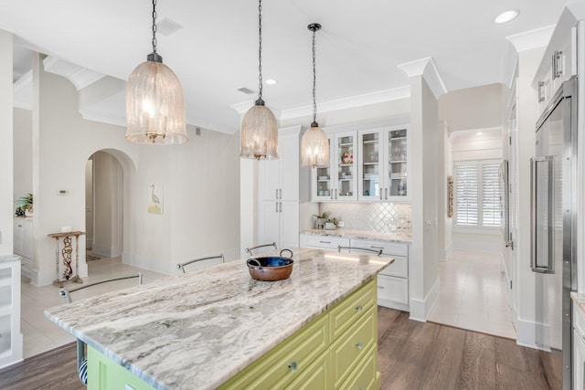 kitchen with white cabinetry, arched walkways, crown molding, and decorative backsplash
