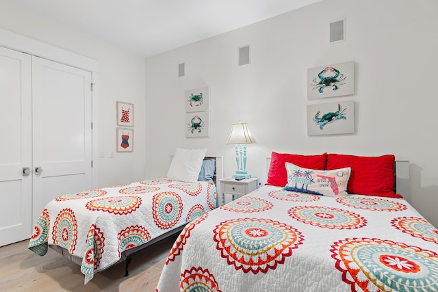 bedroom with visible vents, a closet, and wood finished floors