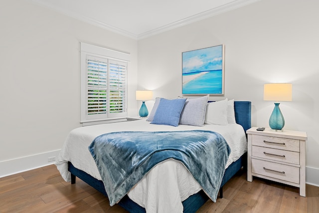 bedroom featuring baseboards, ornamental molding, and wood finished floors