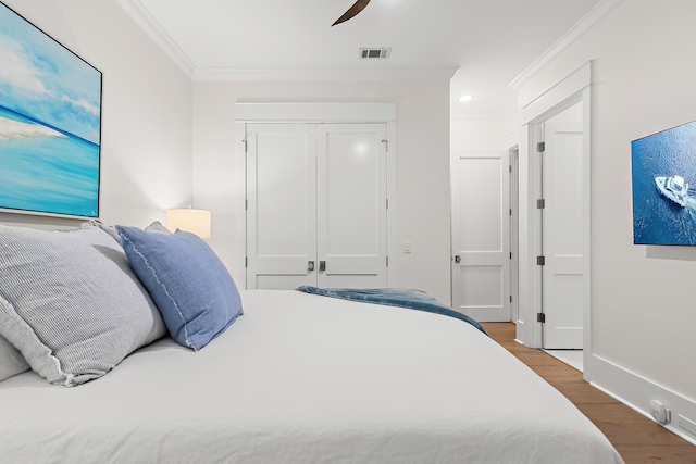 bedroom featuring crown molding, baseboards, visible vents, a closet, and wood finished floors