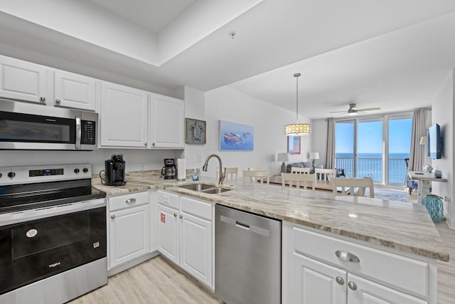 8575 Gulf Blvd Unit 1402, Navarre, FL 32566 - kitchen with a peninsula, stainless steel appliances, white cabinetry, a sink, and light wood-style floors