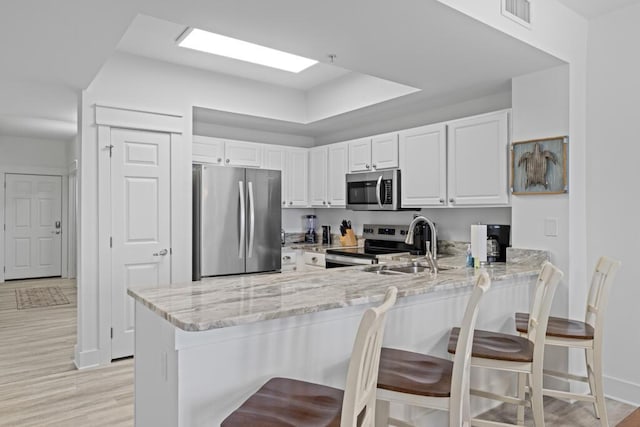 8575 Gulf Blvd Unit 1402, Navarre, FL 32566 - kitchen featuring light stone counters, appliances with stainless steel finishes, a peninsula, visible vents, and white cabinets