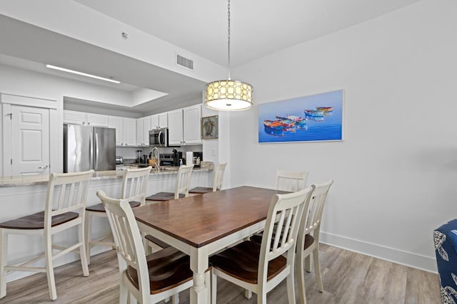 8575 Gulf Blvd Unit 1402, Navarre, FL 32566 - dining room with a raised ceiling, baseboards, light wood-style floors, and visible vents