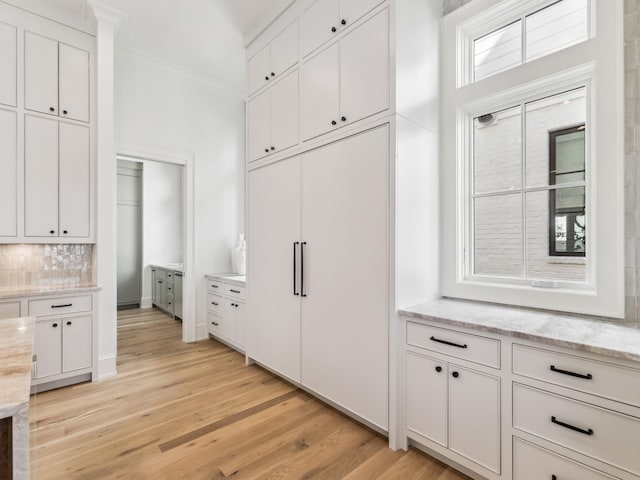 267 Tyler Dr, Santa Rosa Beach, FL 32459 - kitchen featuring crown molding, light stone counters, tasteful backsplash, white cabinets, and light wood-style floors