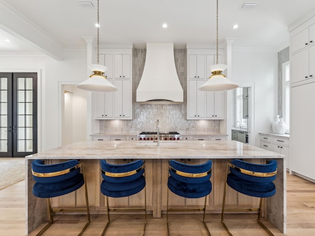 267 Tyler Dr, Santa Rosa Beach, FL 32459 - kitchen with light wood-style flooring, ornamental molding, backsplash, and premium range hood