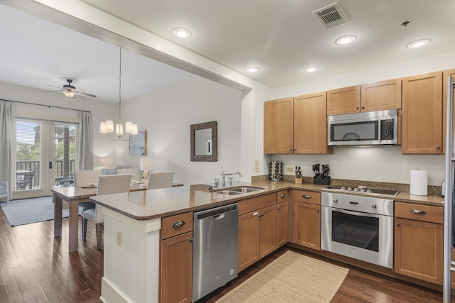 kitchen featuring dark wood finished floors, a sink, visible vents, a peninsula, and appliances with stainless steel finishes