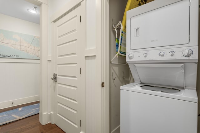 washroom featuring stacked washer and dryer, laundry area, and dark wood-type flooring