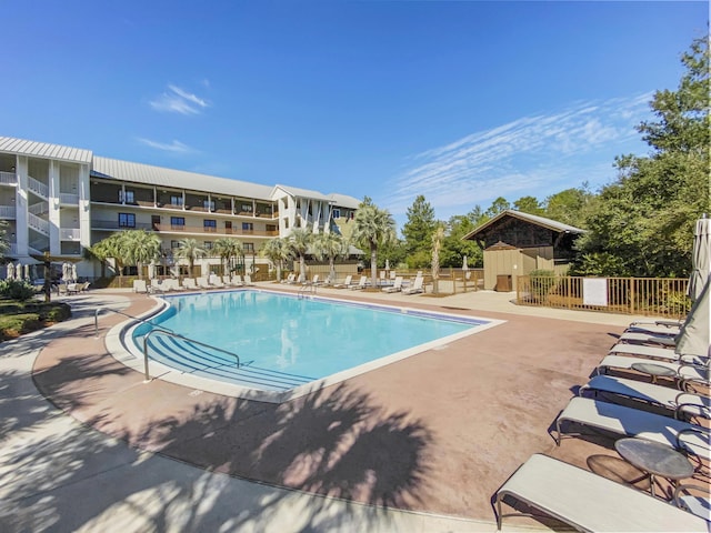 pool featuring a patio area, an outbuilding, and fence