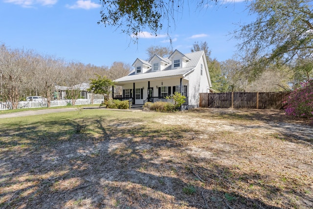 view of front of house featuring a porch, metal roof, a front yard, and fence