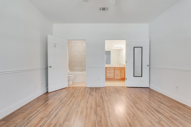 unfurnished bedroom featuring visible vents, baseboards, connected bathroom, and light wood finished floors