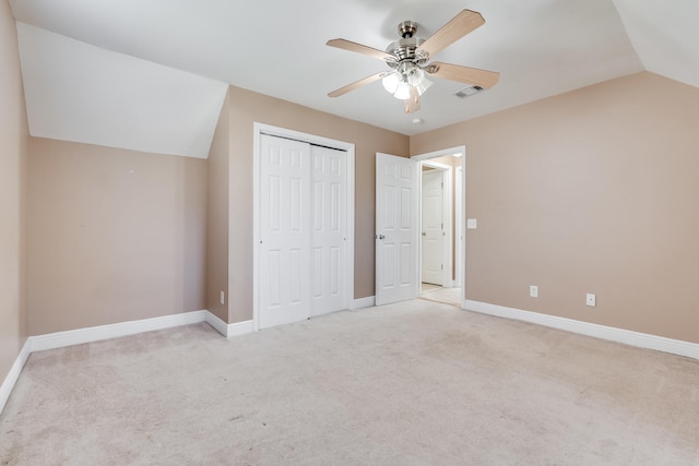 unfurnished bedroom with visible vents, baseboards, lofted ceiling, light carpet, and a closet