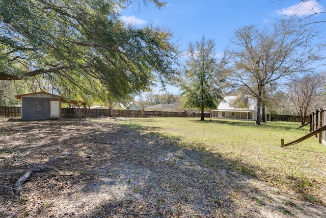 view of yard with a storage shed, an outbuilding, and a fenced backyard