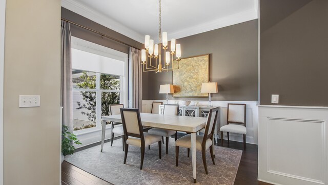 dining space with a wainscoted wall, dark wood-style flooring, a decorative wall, a chandelier, and crown molding