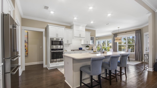 kitchen featuring visible vents, stainless steel appliances, dark wood finished floors, a sink, and an island with sink