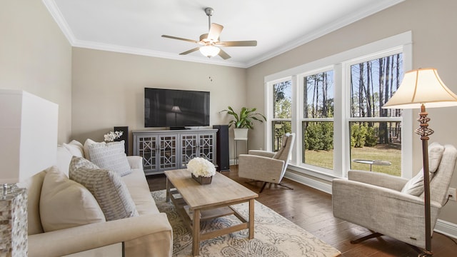 living area with dark wood-type flooring, a ceiling fan, baseboards, and crown molding