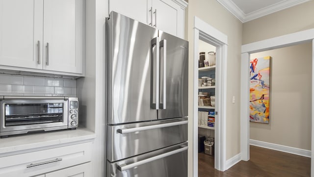 kitchen featuring light countertops, tasteful backsplash, ornamental molding, a toaster, and freestanding refrigerator