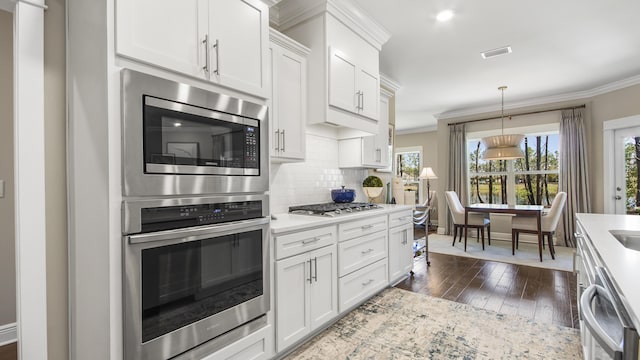 kitchen featuring visible vents, light countertops, decorative backsplash, and ornamental molding