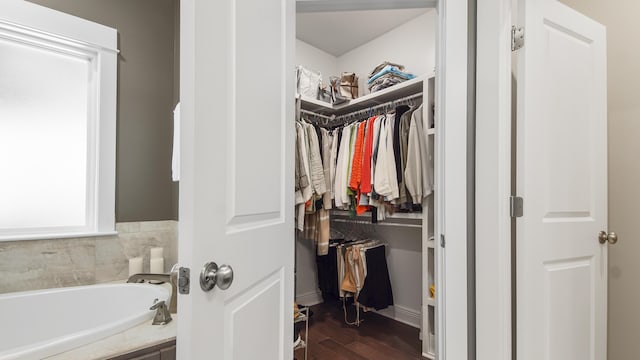 full bath with wood finished floors, a garden tub, and a walk in closet