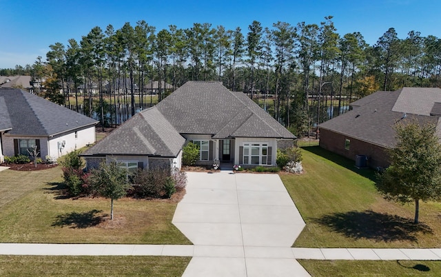 view of front of property with roof with shingles, concrete driveway, and a front yard