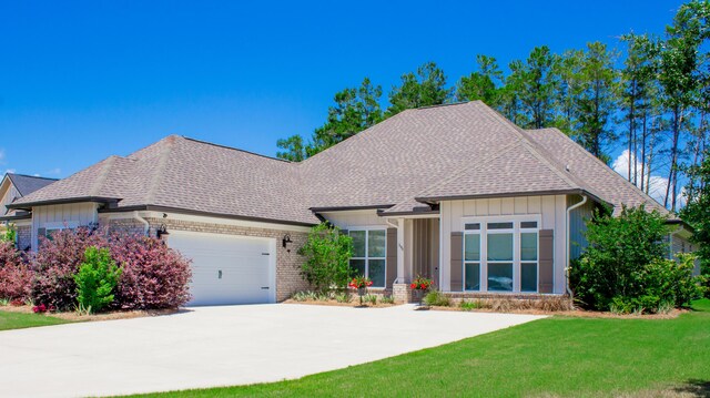 194 Mill Pond Cv, Freeport, FL 32439 - view of front of house featuring board and batten siding, an attached garage, roof with shingles, a front yard, and concrete driveway