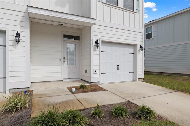 doorway to property with driveway, an attached garage, and board and batten siding