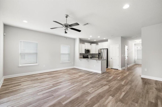 unfurnished living room with baseboards, visible vents, light wood-style floors, ceiling fan, and recessed lighting