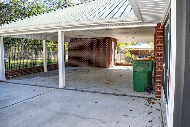 view of parking / parking lot featuring fence and an attached carport