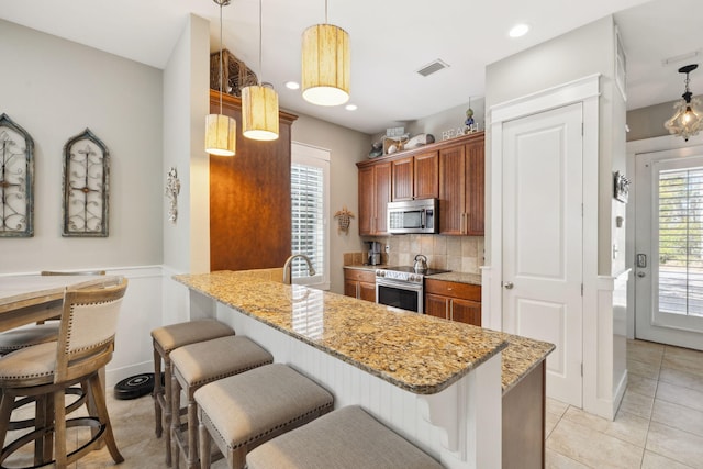 26 Classic Court Ln, Santa Rosa Beach, FL 32459 - kitchen with stainless steel appliances, a peninsula, visible vents, and a breakfast bar