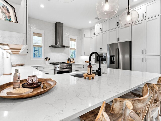 290 White Cottage Rd, Santa Rosa Beach, FL 32459 - kitchen with light stone counters, a breakfast bar area, a sink, premium appliances, and wall chimney exhaust hood