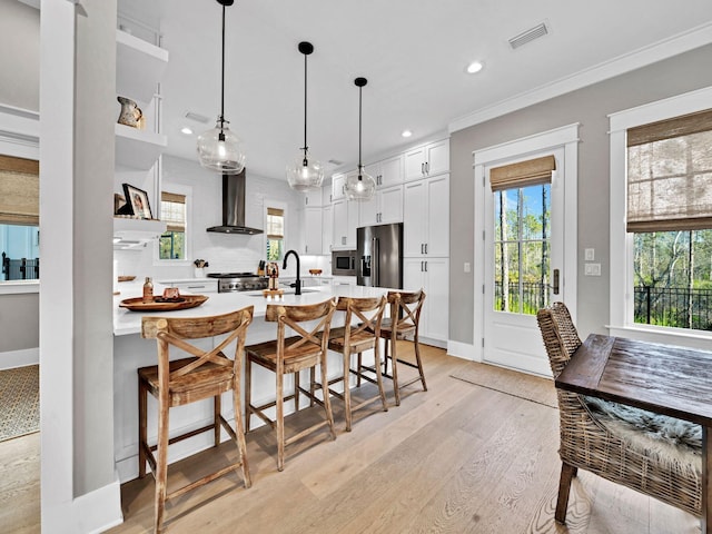 290 White Cottage Rd, Santa Rosa Beach, FL 32459 - kitchen featuring light wood-type flooring, visible vents, wall chimney range hood, light countertops, and appliances with stainless steel finishes
