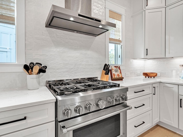 290 White Cottage Rd, Santa Rosa Beach, FL 32459 - kitchen with white cabinetry, tasteful backsplash, stainless steel gas stove, light stone countertops, and wall chimney exhaust hood