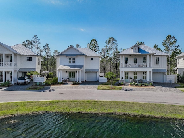 290 White Cottage Rd, Santa Rosa Beach, FL 32459 - view of front facade featuring a balcony, a water view, covered porch, driveway, and an attached garage