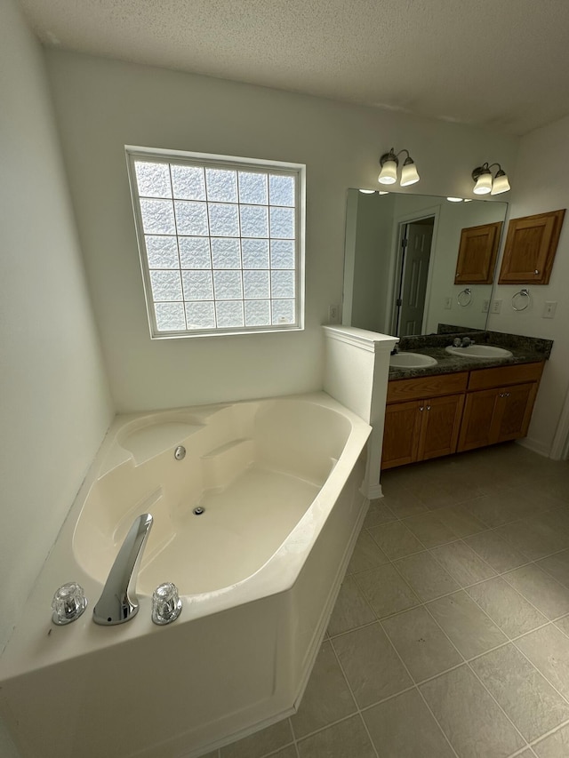 bathroom featuring double vanity, a textured ceiling, a sink, and a garden tub
