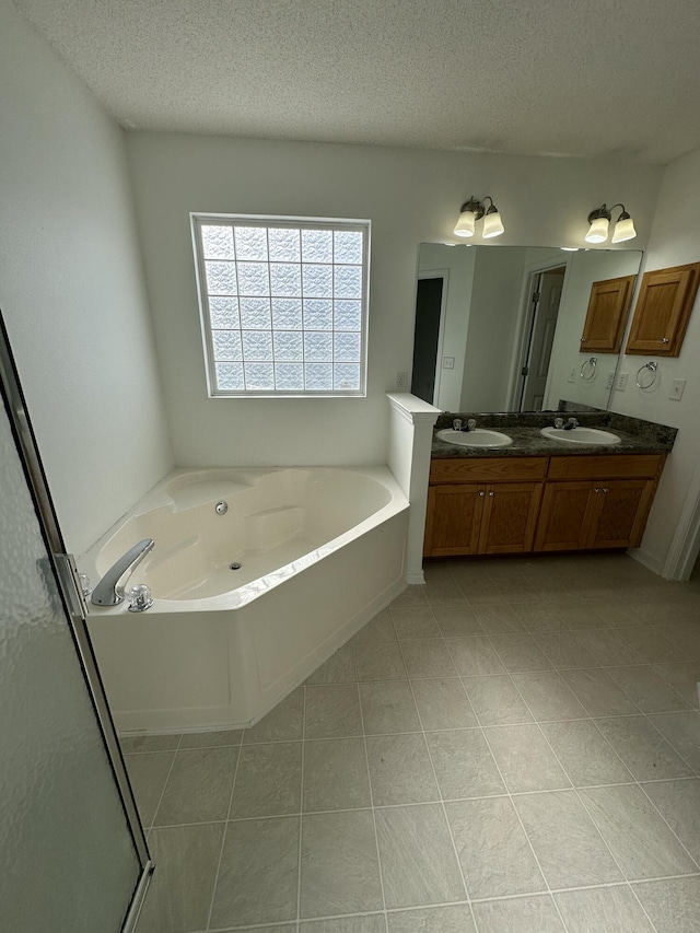 bathroom with double vanity, a textured ceiling, a sink, and a garden tub