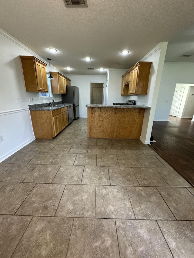 kitchen featuring crown molding, a sink, a textured ceiling, a peninsula, and brown cabinetry