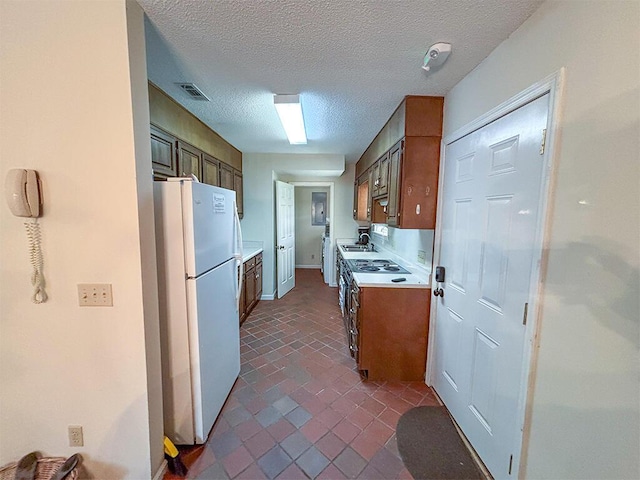 kitchen with light countertops, a textured ceiling, a sink, visible vents, and freestanding refrigerator