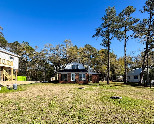 exterior space with a gambrel roof, stairs, and a lawn