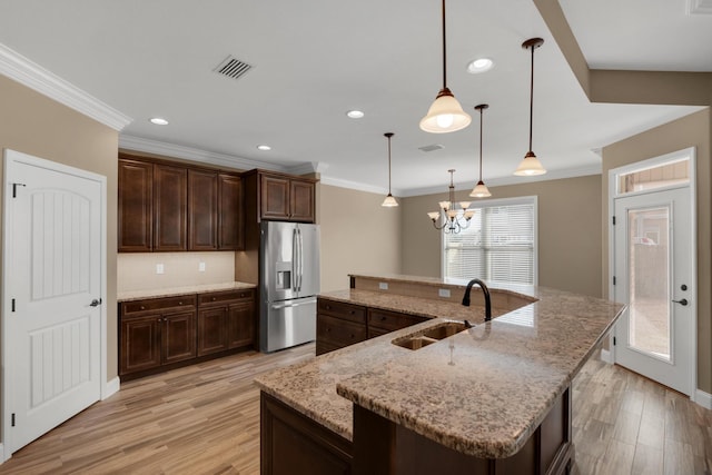 kitchen with light wood-style flooring, stainless steel fridge, a sink, and visible vents