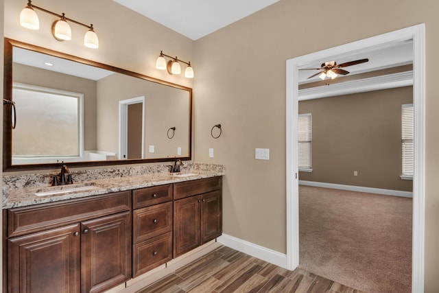 bathroom featuring baseboards, double vanity, a sink, and a ceiling fan