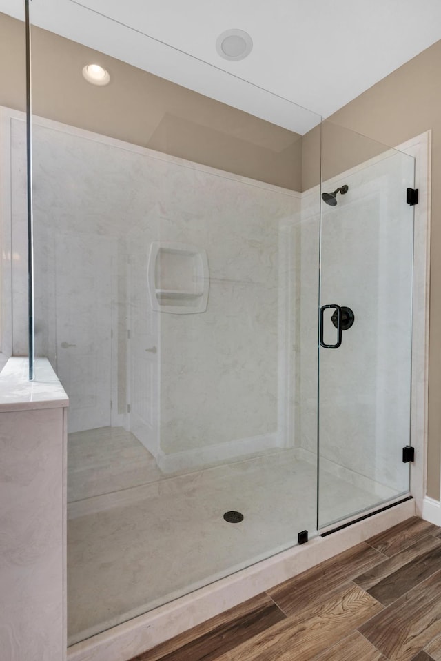full bathroom featuring a shower stall and wood finished floors