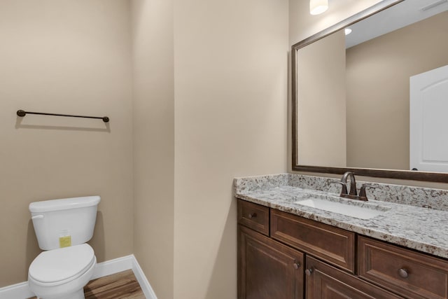 bathroom featuring vanity, toilet, baseboards, visible vents, and wood finished floors