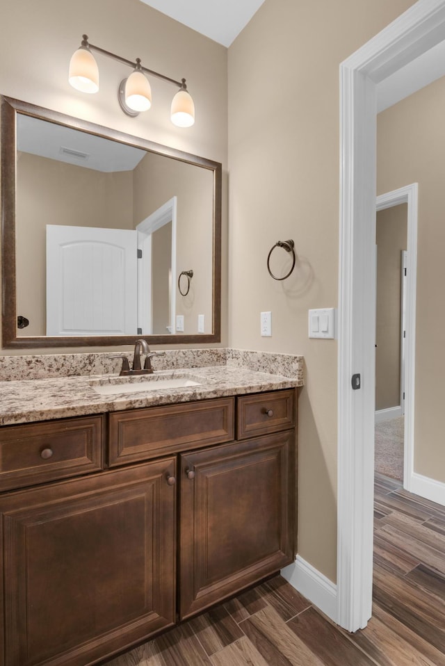 bathroom featuring baseboards, visible vents, wood finished floors, and vanity